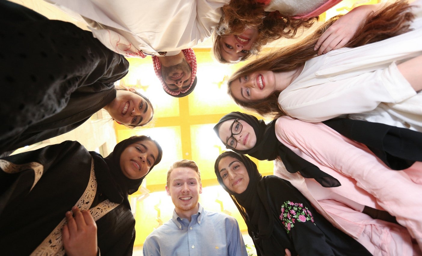 Image of Georgetown students standing in a circle looking down into the camera lense