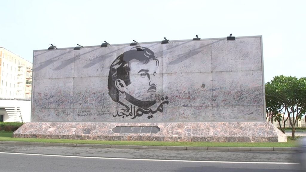 Bilboard with drawing of the Amir of Qatar's face with the inscription "Tamim Al Majd" in Arbic, with support grafitti written on the bilboard.